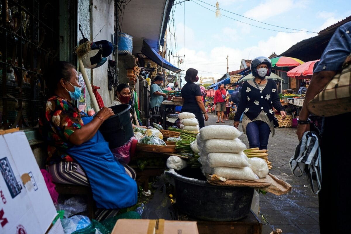 A lively scene from Denpasar featuring a bustling market, traditional Balinese architecture, and colorful street activities.
